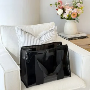 Black tote bag on a white couch with a vase of flowers and books in the background #color_midnight black