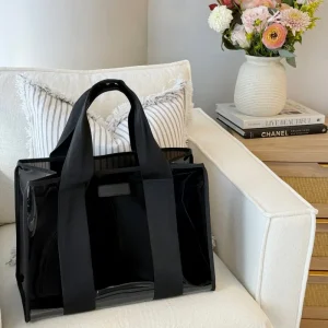 Black bag on a white couch with a vase of flowers and books in the background #color_midnight black