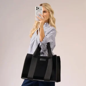 Woman holding a black tote bag with a neutral background #color_midnight black