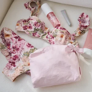 Floral swimsuit with pink pouch and skincare products on a light surface #color_ballet pink bow