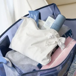 Open suitcase with folded clothes and toiletries on a neutral background #color_ivory pearl bow