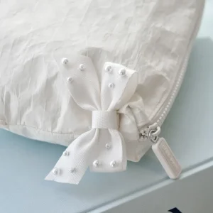 White cap with a decorative bow and pearls on a light blue background #color_ivory pearl bow