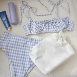 Blue and white checkered bikini set with a towel and sunscreen on a light background #color_ivory pearl bow